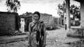 An Indian woman standing in a street with rough dirt roads