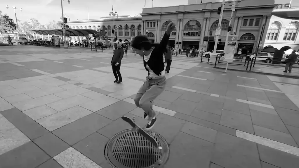 A girl doing a kick flip on a skateboard in the city.