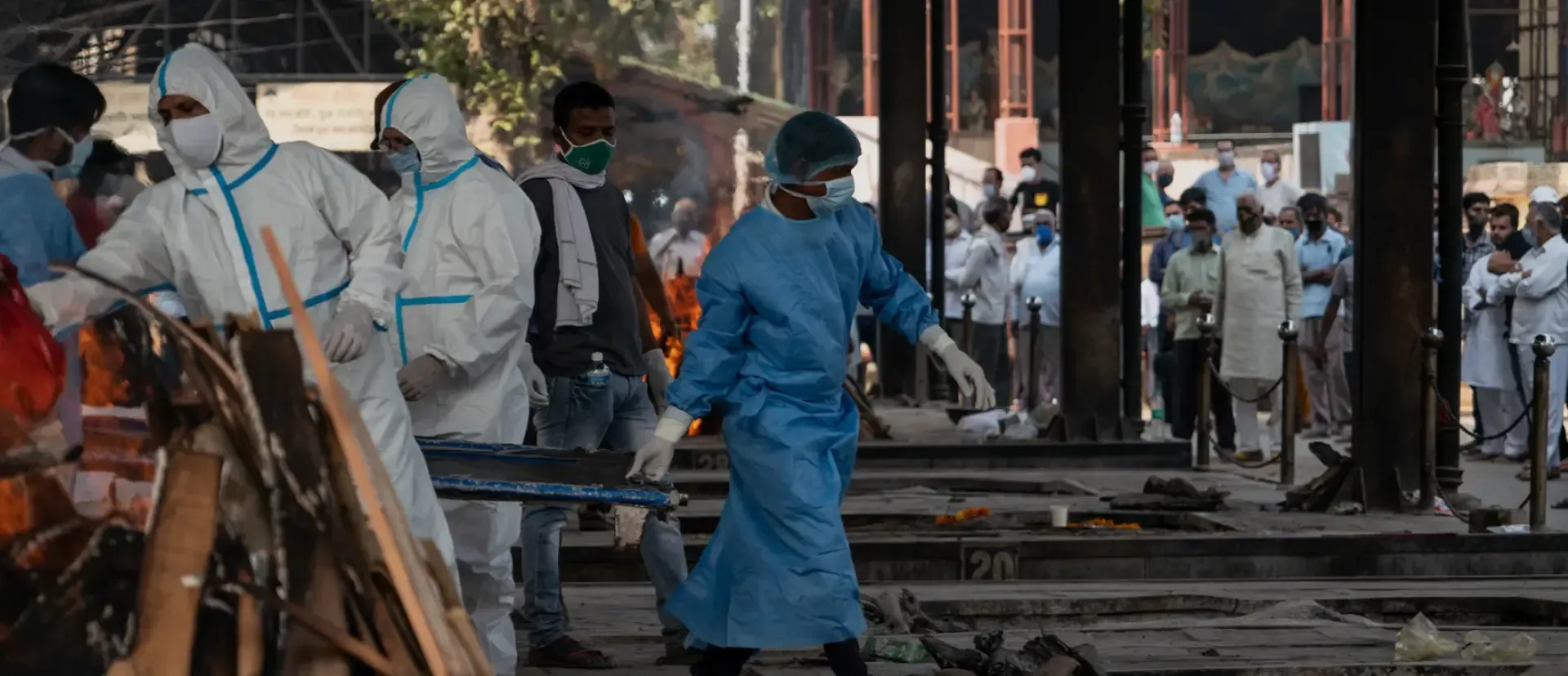 Ambulance drivers in PPE carry wood to pyres at a cremation ground in New Delhi.