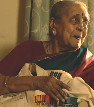 An elderly indian lady in a saree holding her Indian Air Force uniform shirt