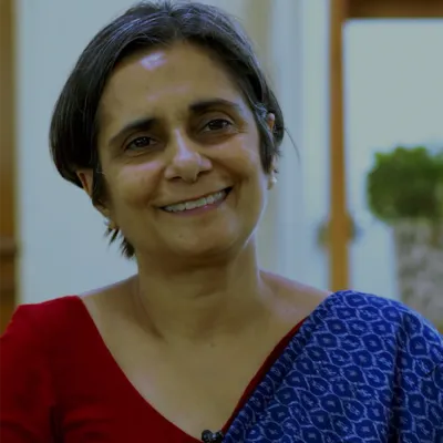 An Indian woman wearing a saree smiling while giving an interview