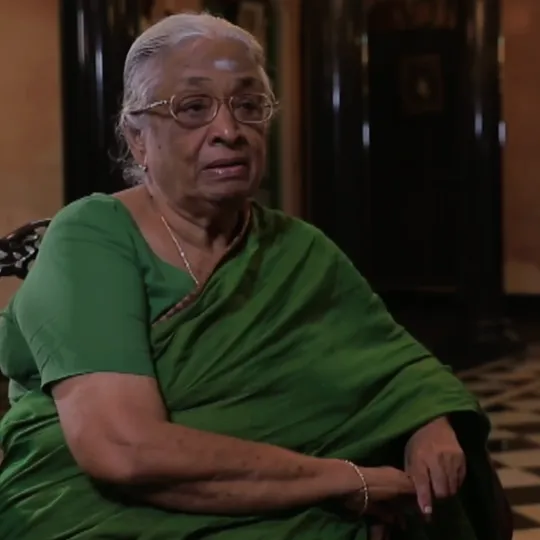 An elderly indian lady in a saree giving an interview while sitting