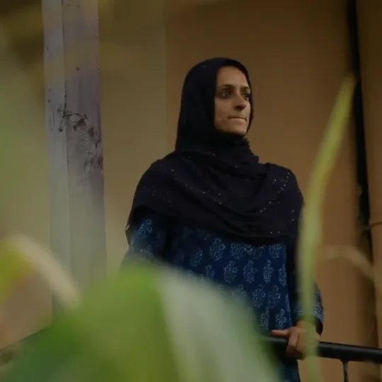 An indian lady in a hijab looking over her balcony